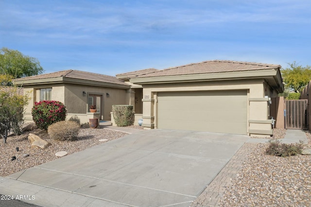 view of front facade with driveway, an attached garage, fence, and stucco siding