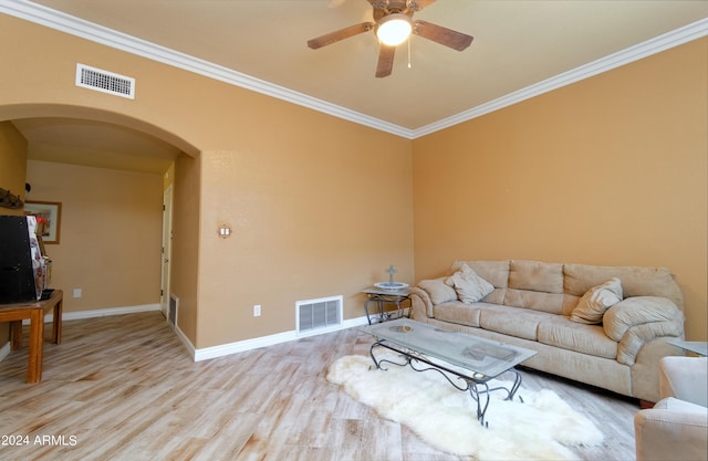 living area featuring light wood-style floors, arched walkways, visible vents, and ornamental molding