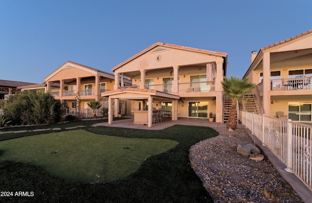 rear view of property featuring outdoor dry bar, stucco siding, a patio area, fence, and a balcony