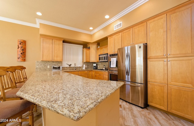 kitchen featuring visible vents, appliances with stainless steel finishes, a breakfast bar area, a peninsula, and light brown cabinets