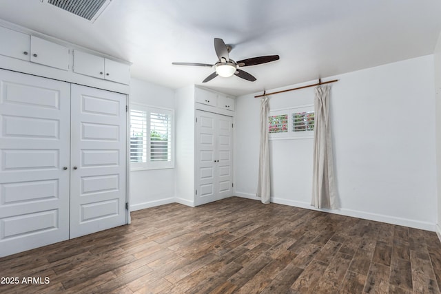 1334 W Sells Dr, Phoenix, AZ 85013 - unfurnished bedroom featuring multiple closets, dark wood-style flooring, baseboards, and a ceiling fan