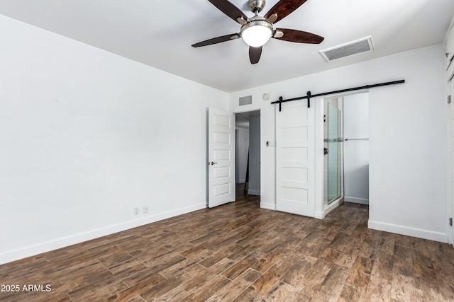 1334 W Sells Dr, Phoenix, AZ 85013 - unfurnished bedroom featuring a barn door, dark wood finished floors, baseboards, and a ceiling fan