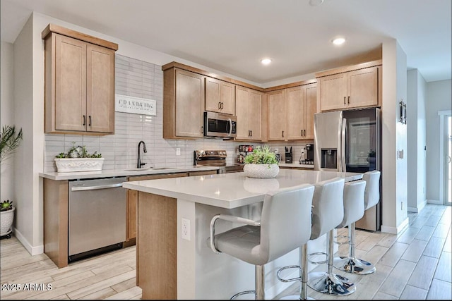 16955 W Butler Ave, Waddell, AZ 85355 - kitchen with stainless steel appliances, a sink, backsplash, wood finish floors, and a kitchen bar