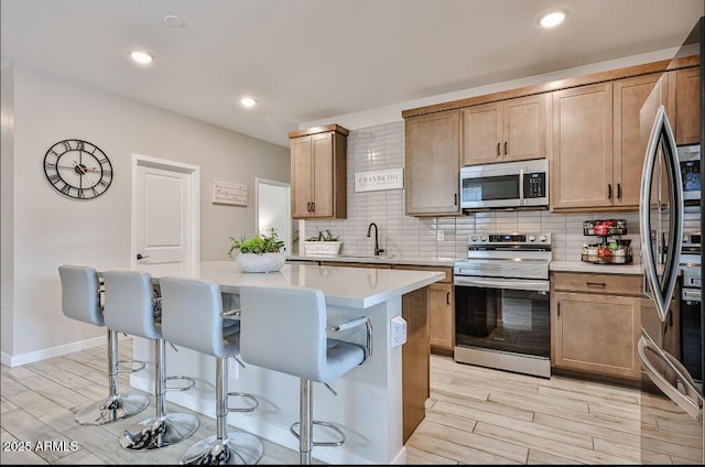 16955 W Butler Ave, Waddell, AZ 85355 - kitchen with appliances with stainless steel finishes, light wood-type flooring, a kitchen breakfast bar, a sink, and recessed lighting