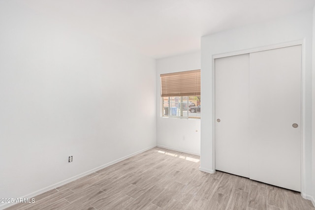 12132 W Dahlia Dr, El Mirage, AZ 85335 - unfurnished bedroom with light wood finished floors, a closet, and baseboards