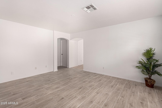 12132 W Dahlia Dr, El Mirage, AZ 85335 - empty room featuring light wood-style floors and arched walkways