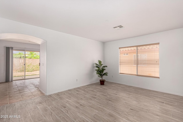 12132 W Dahlia Dr, El Mirage, AZ 85335 - unfurnished room featuring light wood finished floors, arched walkways, and baseboards