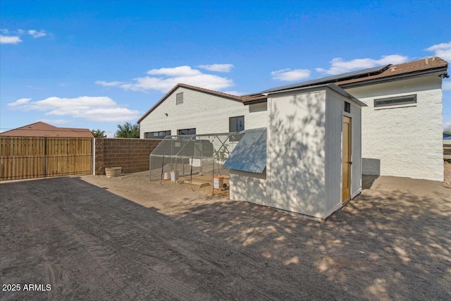 20715 E Watford Dr, Queen Creek, AZ 85142 - rear view of house with an outbuilding, roof mounted solar panels, fence, and exterior structure