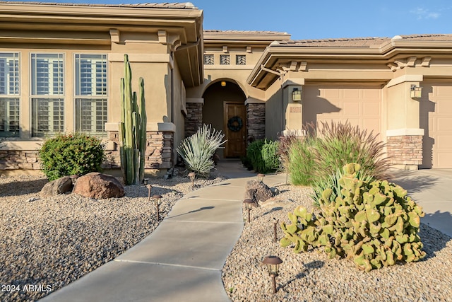 view of front of property featuring an attached garage, stucco siding, stone siding, and a tile roof