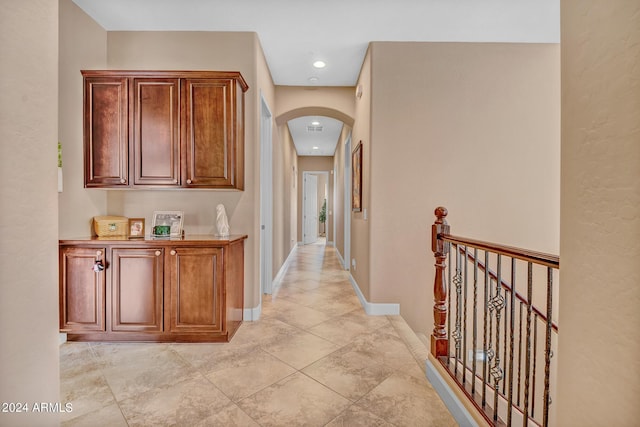hallway featuring baseboards, an upstairs landing, arched walkways, and recessed lighting