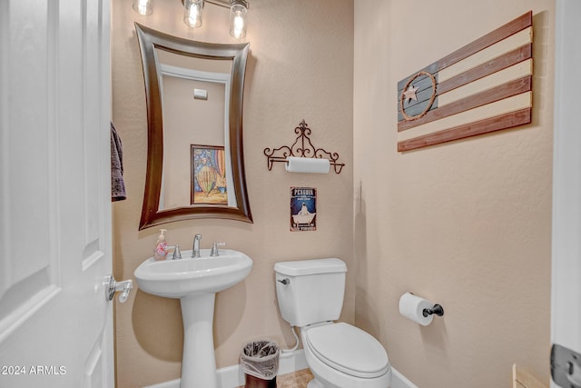 bathroom featuring a sink, toilet, and baseboards