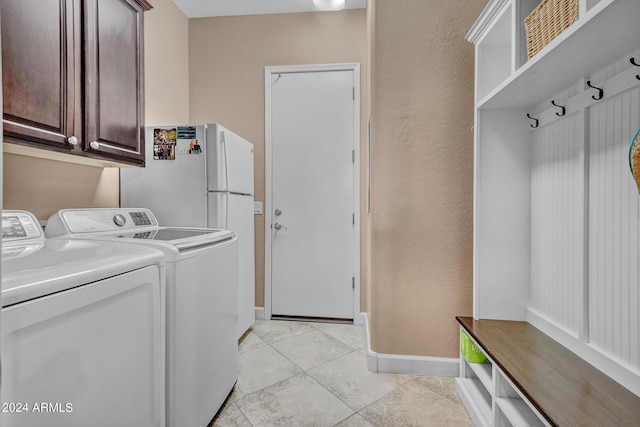 washroom featuring light tile patterned flooring, washing machine and dryer, baseboards, and cabinet space