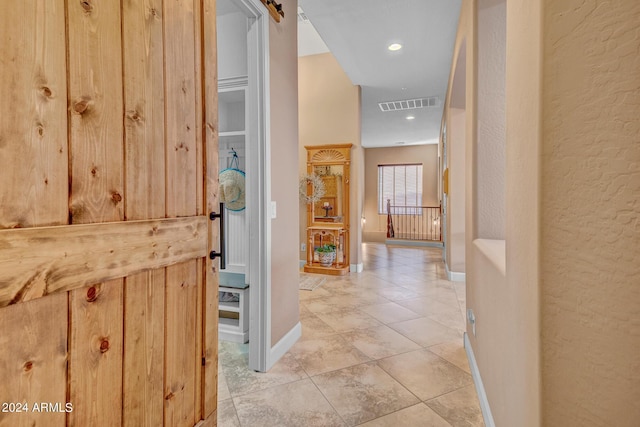 hall with visible vents, baseboards, light tile patterned floors, a textured wall, and recessed lighting