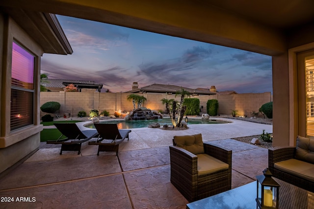 patio terrace at dusk with a fenced in pool and a fenced backyard
