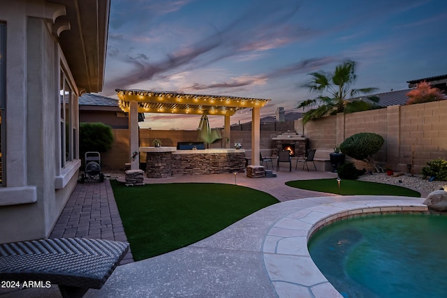 view of yard featuring a patio area, a fenced backyard, a pergola, and an outdoor kitchen