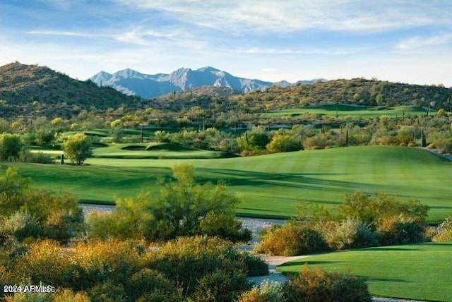 view of home's community with a yard, a mountain view, and view of golf course