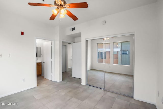 unfurnished bedroom with ensuite bath, a closet, and ceiling fan