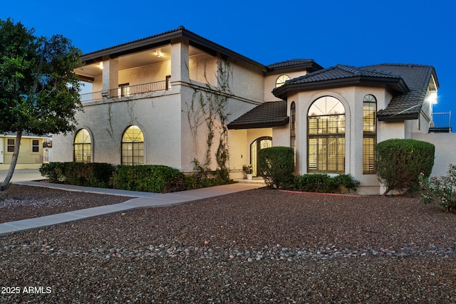 mediterranean / spanish home with stucco siding, a tiled roof, and a balcony