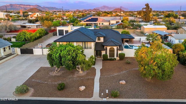 view of front of home with driveway, a residential view, stucco siding, a mountain view, and fence
