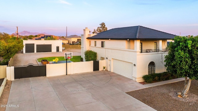 view of front of home with stucco siding, a gate, driveway, and a balcony