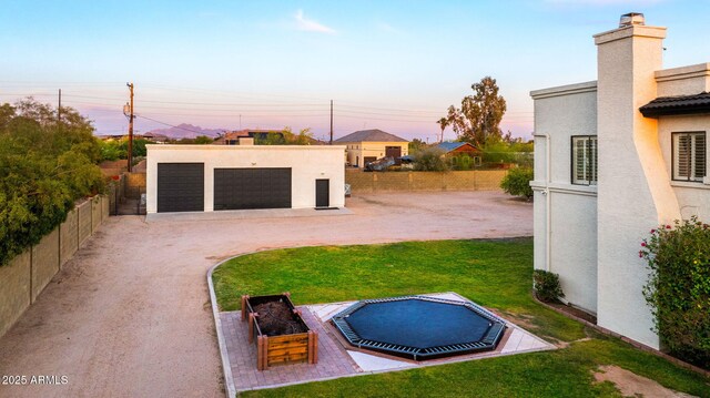 yard at dusk featuring fence, an outdoor structure, and a garage