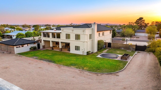 rear view of property featuring a patio, a yard, a chimney, stucco siding, and fence