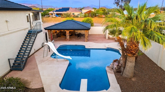 outdoor pool featuring a fenced backyard, a gazebo, a water slide, a patio area, and stairs