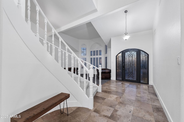 entryway featuring stairs, arched walkways, stone tile flooring, and baseboards