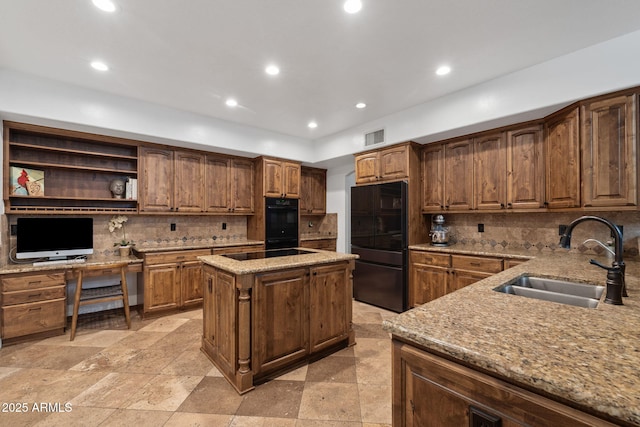 kitchen with decorative backsplash, a sink, visible vents, black appliances, and light stone countertops
