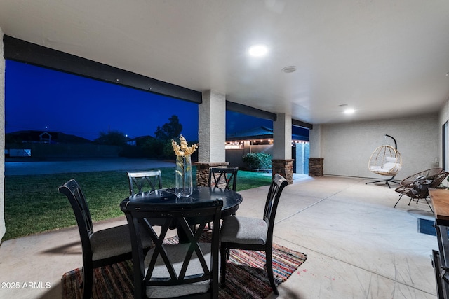 patio at night featuring fence, outdoor dining space, and a yard
