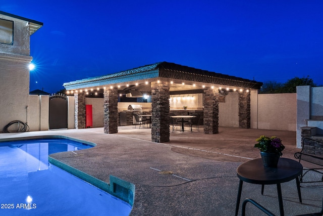 pool at twilight with area for grilling, a fenced in pool, and a patio area