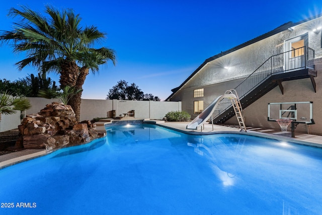 view of swimming pool with a water slide, a fenced backyard, a fenced in pool, and stairs