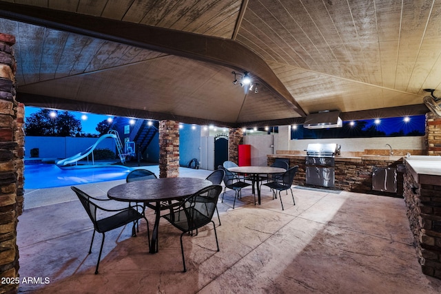 patio at twilight featuring fence, area for grilling, outdoor dining area, a grill, and an outdoor pool