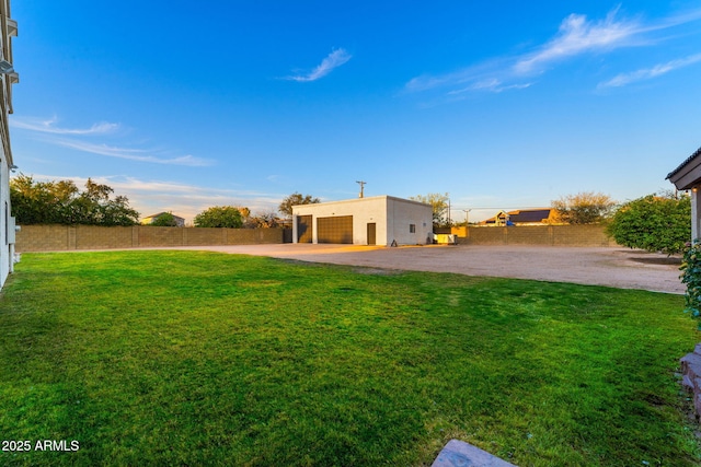 view of yard with an outbuilding, a garage, and a fenced backyard