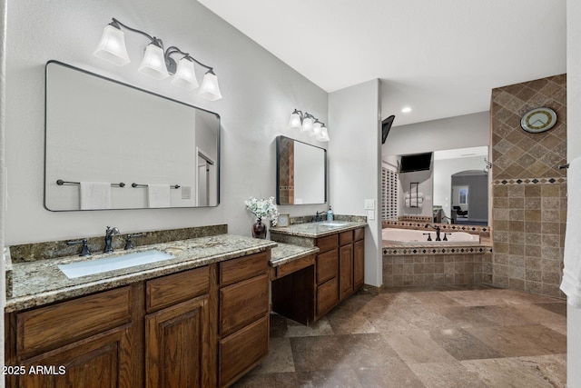 bathroom with stone finish flooring, two vanities, a bath, and a sink