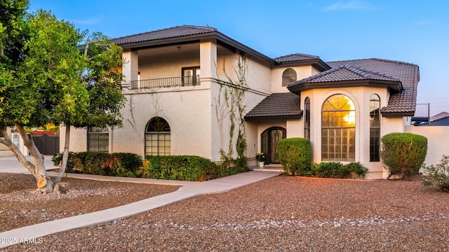 mediterranean / spanish home with stucco siding, a tiled roof, and a balcony