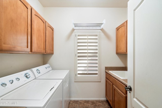 laundry area featuring cabinet space, washing machine and dryer, a sink, baseboards, and tile patterned floors