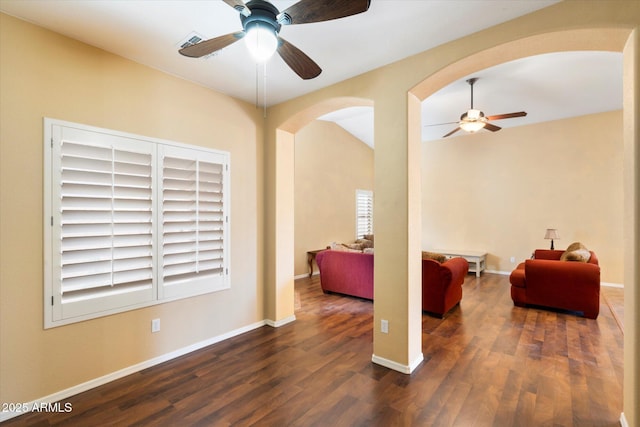 interior space with arched walkways, ceiling fan, wood finished floors, visible vents, and baseboards