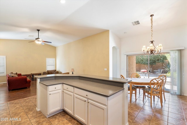 kitchen with light tile patterned floors, visible vents, lofted ceiling, hanging light fixtures, and white cabinetry