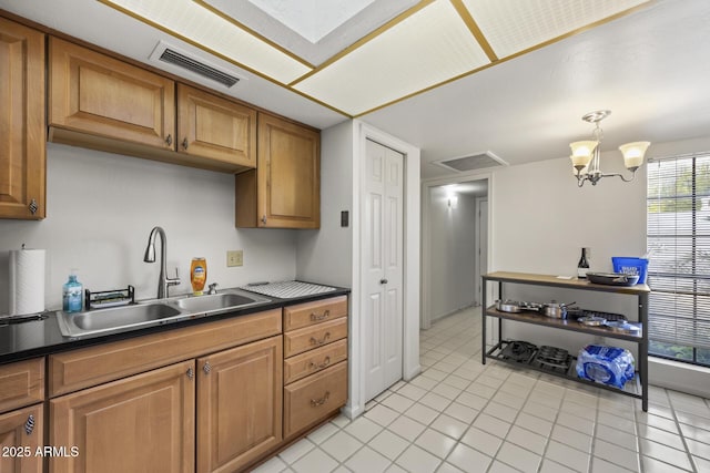 kitchen featuring light tile patterned floors, a chandelier, decorative light fixtures, and sink