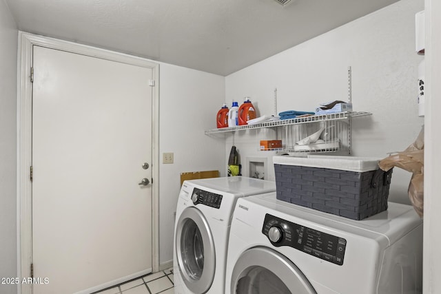 clothes washing area featuring washing machine and dryer and light tile patterned floors