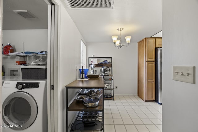 laundry room featuring light tile patterned floors, washer / dryer, and a chandelier