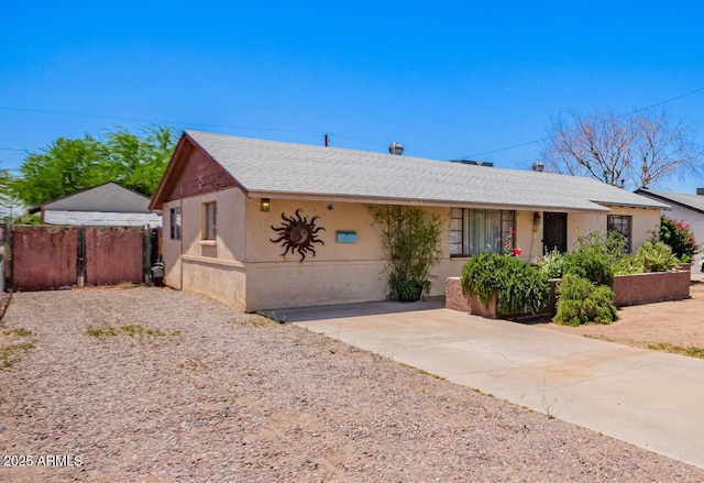view of front of property featuring roof with shingles, stucco siding, and fence