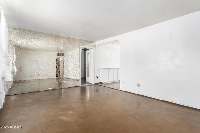 unfurnished room with arched walkways, finished concrete flooring, radiator heating unit, and baseboards