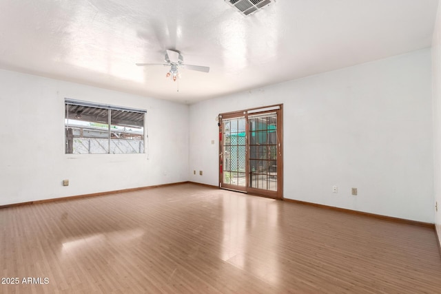 unfurnished room with healthy amount of natural light, wood finished floors, and a ceiling fan