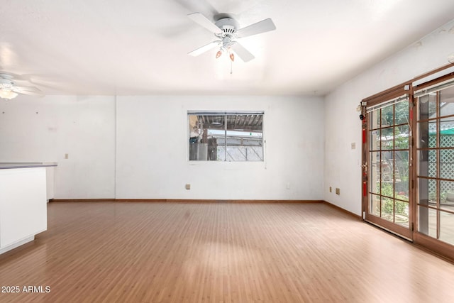 empty room with ceiling fan, wood finished floors, and baseboards
