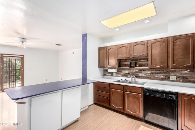 kitchen featuring black dishwasher, a sink, a peninsula, light wood-style flooring, and tasteful backsplash