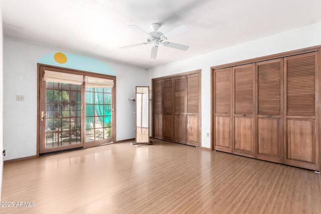 unfurnished bedroom with light wood finished floors, multiple closets, access to outside, baseboards, and a ceiling fan