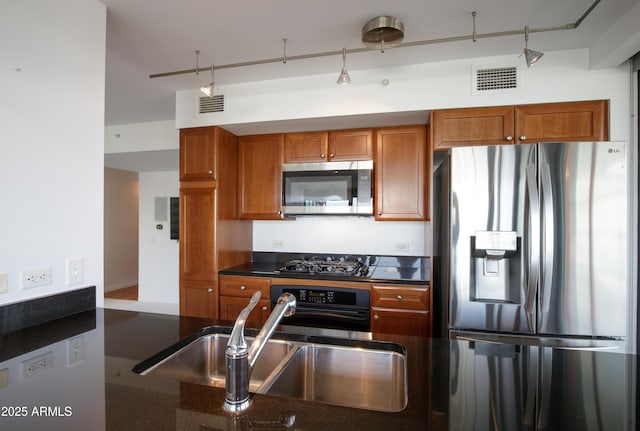 kitchen featuring appliances with stainless steel finishes, brown cabinetry, visible vents, and a sink