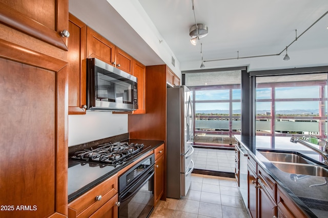 kitchen featuring light tile patterned flooring, a sink, brown cabinets, black appliances, and track lighting